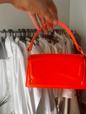Skrik orange väska - Relativt liten väska, härlig färg as snyggt till sommaren och liva upp en outfit! Säljer pga köpte fel till balen så aldrig anvönd
