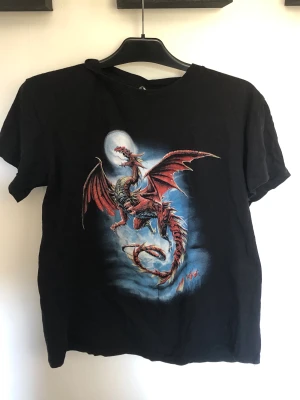 T shirt med tryck i stl S. Svart T shirt - Denna T shirt med tryck är i stl S och är gjord av bomull. Den är i fint skick.