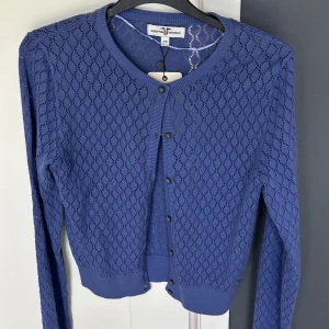 Cardigan  - Cardigan Hampton republic från Kappahl. Aldrig använd , etikett är kvar.  Normal i storlek och mycket bra material och i fin blå/lavendel färg.