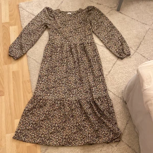 En svart blommig kläning - En svart klänning med orange/beige blommor, köpt från next o skulle säga den var s-xs. Ganska kort i ärmarna men snyggt. Perfekt för hösten🍂🍂