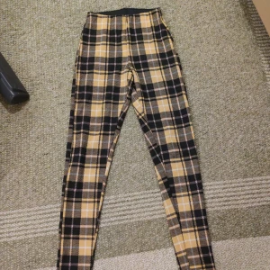 Leggings - Gul svart rutiga leggings, tighta och lite tjockare material än vanliga tygg leggings Ser ljus gula ut på bilden men jag skulle säga att dom är mer orange gula irl
