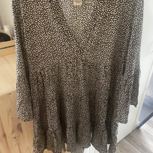 Klänning - Klänning med trumpetärm och blommönster. Sparsamt använd.