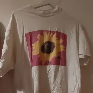 Ganska stor t-shirt med tryck av en solros på framsidan. Köpt secondhand men bra skick. 