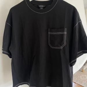 T-shirt - Säljer denna coola T-shirten från monki. Svart med vita sömmar. Använd fåtal gånger så bra skick. 