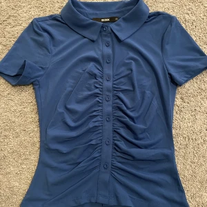 Blå tröja - Blå tröja med knappar och scrunch på framsidan! Jätte fin sitter väldigt fint på också! Säljs pågrund av att jag inte tyckte den passade mig. Den är mer klar blå i verkligheten! Använd Max 1 gång. Vid fler frågor eller bilder kom privat💗 du står för frakt