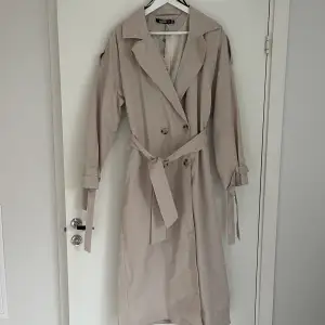 Beige trench coat helt oanvänd lapp kvar!  Köpt från missguided för ca 2 år sedan storlek 36. Nypris 800kr Köparen står för frakten 