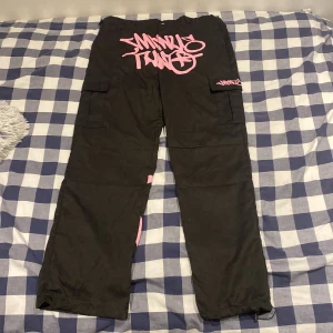 Minus two cargo pants pink. - Ett par svarta minus two cargo pants med rosa text på fram och baksida. De är baggy, sköna och sitter bra. Om du vill att den ska sitta bättre rekommenderar jag att använda ett bälte! Dm för flera bilder och ställ alla era frågor!