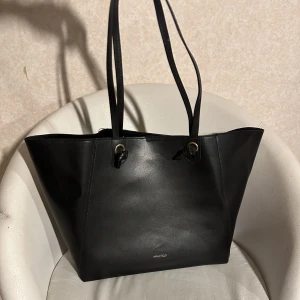 Svart handväska - Säljer min fina handväska som tyvärr inte kommer till användning. Väskan är i mycket bra skick utan några defekter. Den är mycket rymlig och har ett litet fack inuti. Jag köpte den för 2 år sedan från Zalando för ungefär 400kr. Pris kan diskuteras❣️