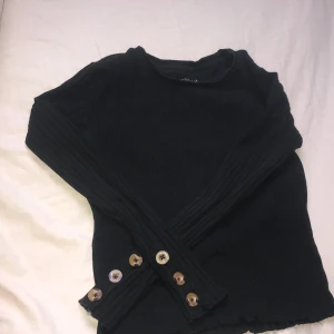 Svart långarmad tight tröja - Xoxo❤️friends  S men kan vara liten i storlek Lånarnas, svart med bruna knappar o lite kort vid längden. Nästan crop top