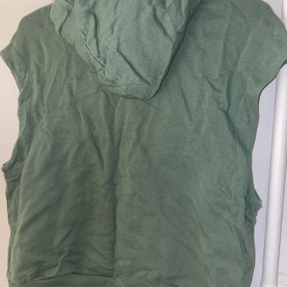 En armlös grön huvtröja från H&M, använd men inga defekter. Storlek S.. Hoodies.