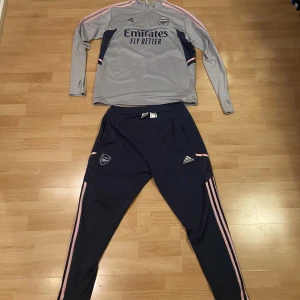 Arsenal tränings kit 22/23  - Arsenal träningskit tröja och byxa  Byxorna  är helt som i nyskick 10/10  Tröjan har ett lite slitage 9/10 Båda är i st L Går att sälja var för sig om man kommer med bud. 