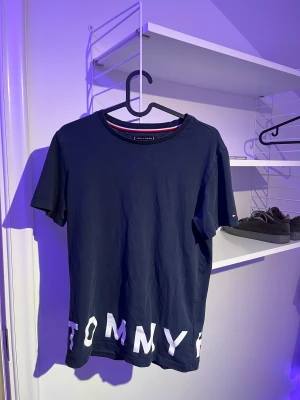 Tommy hilfiger tshirt - Säljer min Tommy hilfiger T-shirt mörkblå med text längst ner på framsidan och baksidan storlek 164
