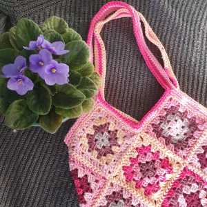 Granny Square Väska - Rosa - Granny square väska gjord i bomull, akryl och ullgarn med blandade nyanser🌸 Väskan är ca 28 cm i bredd och ca 28 cm i längd. Räknar man med axelremmen är väskan 52 cm i längd totalt🌼 (kort axelremm) Frakt ej inräknad i priset💕