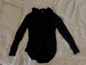 Svart blus med detaljer - Super fin svart blus med fina volang detaljer vid halslinje och vristerna. Går att knäppa upp och ner beroende på önskad stil. Sitter ljuvligt på!