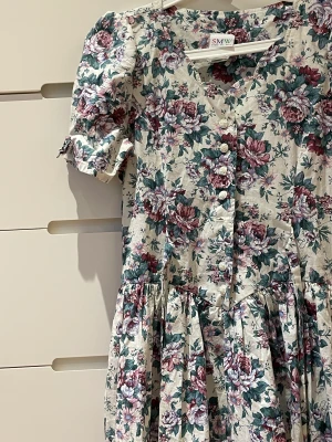 Vintage klänning - Supergullig vintage klänning i ett superfint blommigt tyg. Det finns ett band som man kan knyta där bak (se bild tre) som man kan styra storleken runt midjan med. Säljs för att den inte används men hoppas verkligen att den får ett nytt hem!❤️
