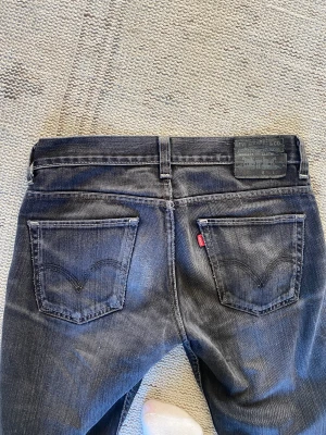 Raka Levis jeans - Asnajs svarta Levis jeans med hål på ena knät. Perfekta svarta paret till hösten, stolen 30/32. Jag har storlek 36/38 och är 170 cm, perfekt längd