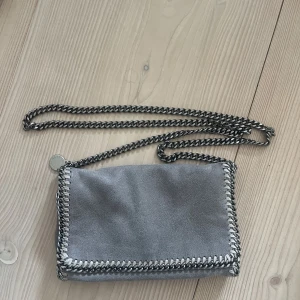 Stella McCartney väska - Säljer en Stella McCartney axelväska!🤍🤍🙌🏽 Den är i en grå färg och har en kedja som tillhör! I bra skick och skriv om du har någon fråga🤍🤍