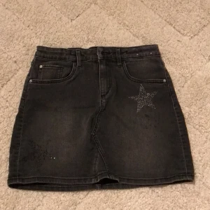 Jeans kjol med stjärnor - Säljer denna skjukt snygga denim kjol med silvriga stjärnor på! Två av de svarta stjärnorna där fram är lite avskavda som man ser på den tredje bilder därav priset. Köpte den för rätt så länge sen men föruton stjärnorna så är själva kjolen i bra skick!❤️💗💗