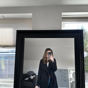 Svart kappa - En svart kappa med bälte. Köpte för många år sedan & den är lite för liten nu. Skulle säga att den passar en XS. Använd men utan skador!