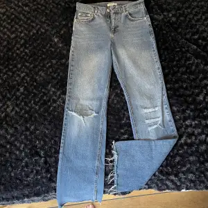 Mellanblå fina jeans med revor framtill samt på vänster bakficka. 6 cm slits nertill med fransar, se bild! Knappt använda och mkt fint skick. 
