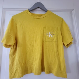 Calvin Klein t-shirt  - Jättefin gul Ck t-shirt, i mycket gott skick, så fin nu till sommaren! Lite croppad, så kort i storleken 