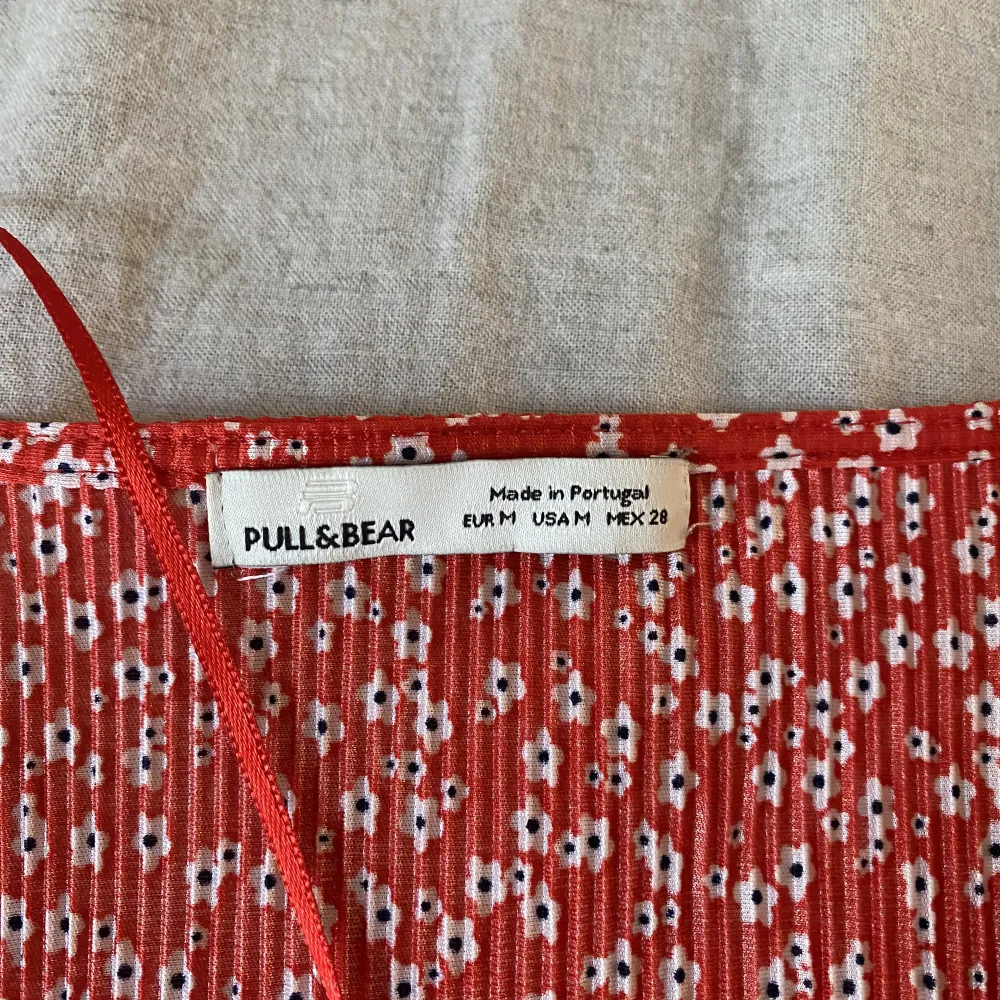 En röd byxdress från Pull&Bear med vita blommor på. Andvänd ca 2-3 ggr och är i storlek M. Klänningar.