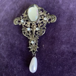 Sirlig brosch  - En vackert utsirad brosch med hängande pärla Stämplad germany   Okänt material 
