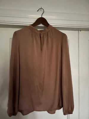 Blus med knappar i halsen - Fin silkig blus i polyester med två klädda knappar i halsen, färg mörkare gammelrosa 