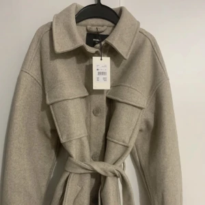 Beige/grå kappa - Hel oanvänd, prislappen sitter kvar. Säljer endast pga den va för stor. Större i storleken, passar nog XS-M beroende på vilken passform man vill ha såklart :)