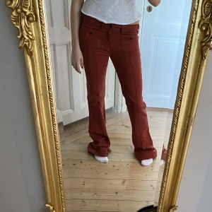 Orangea bootcutjeans - Galet snygga och trendiga jeans i en underbar mörk orange färg💕 Midrise höjd i midjan❣️Utsvängda i benen och har superfina fickor framtill! Materialet är stretchig och jeansen passar M-L, de är väldigt långa i benen. Skriv vid funderingar😇