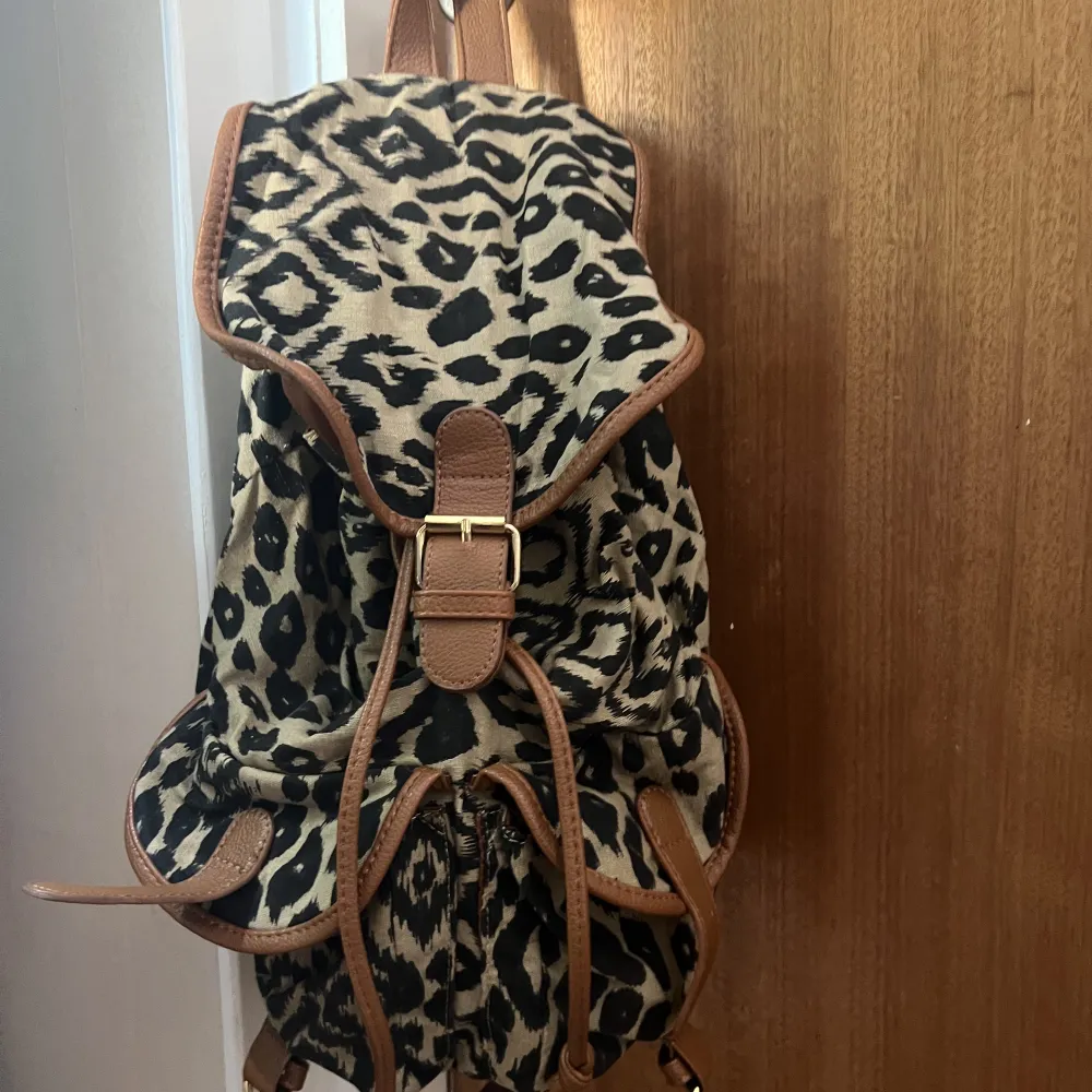 Ryggsäck med två mindre fickor fram, leopard mönster med bruna detaljer . Väskor.