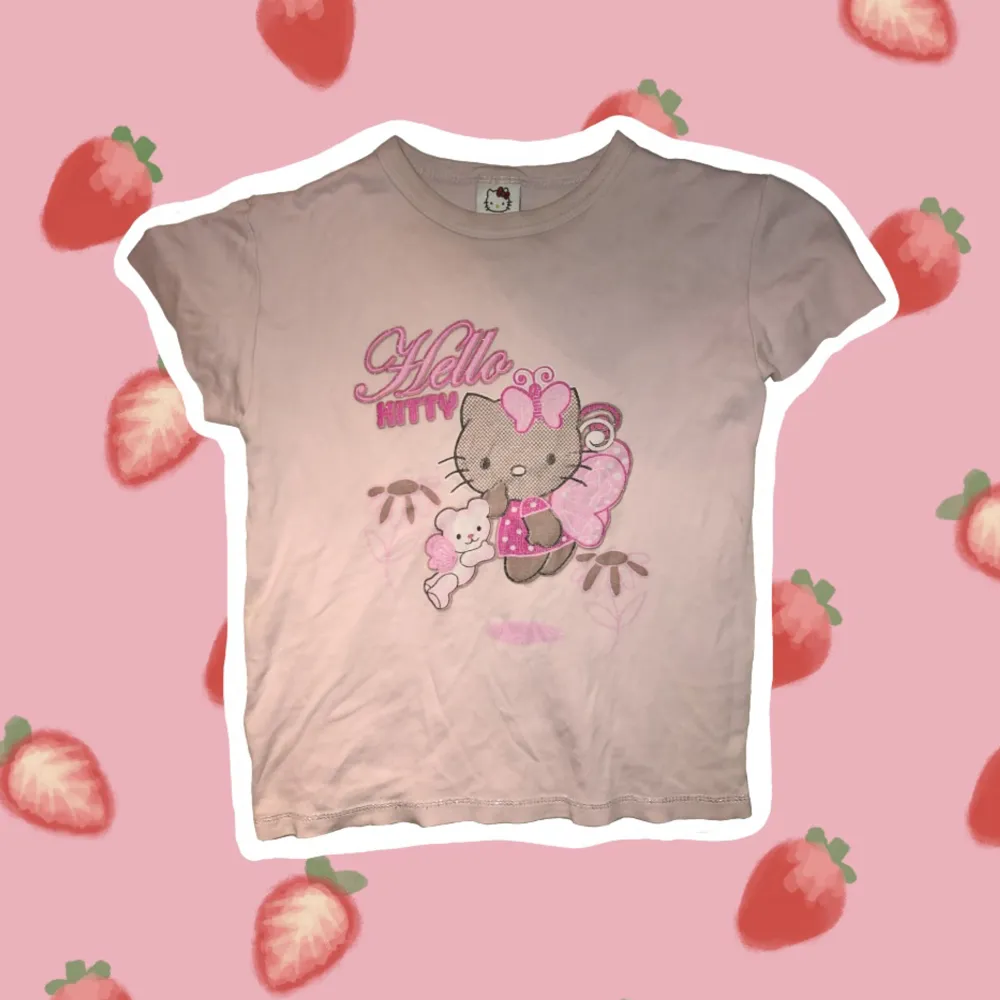 Figurnära Hello Kitty T-shirt, ljus rosa. Det syns knappt på bilderna med nedersta sömmen och allt motiv på T-shirten glittrar lätt. Jag på bild har storlek M. Armarna på T-shirten är bortklippta och har inte ömsat.  . T-shirts.