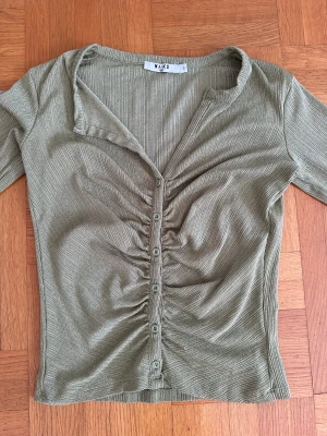 grön lång armad topp!  - Topp i fin grön färg från NA-KD. Tröjan är i polyester och har en modell med ihop skrynkligt tyg i mitten av bysten samt rynkningar vid armarna. (Frakt tillkommer) ganska stor i storlek 