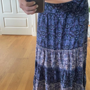 Långkjol - Superfin mönstrad långkjol som går ner lite baktill. Perfekt nu för sommaren💙Storlek M men har en resår bak i midjan vilket gör att den passar som en L också. Köpt secondhand. Bra skick!