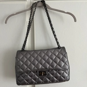 Handväska  - Chanelliknade väska i silver🎀 köpt på judiths i Stockholm, ursprungligen kommer väskan från italien, köpte den frö 900kr säljer för 450. Bra skick, vid låset  har metallen tappat lite färg. Möts och fraktar 💖