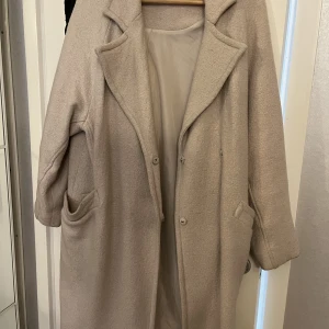Beige höstkappa - En beige och fin höstkappa från Ellos i storlek 34/36. Den är använd några gånger bara så den är i bra skick.