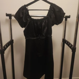 Grå klänning i siden imitation  - VÄNTA PÅ SVAR FRÅN MIG INNAN KÖP! En mörkgrå klänning i siden imitation, med puffärmar och smalnad midja. Fint skick. Katt finns i hemmet!