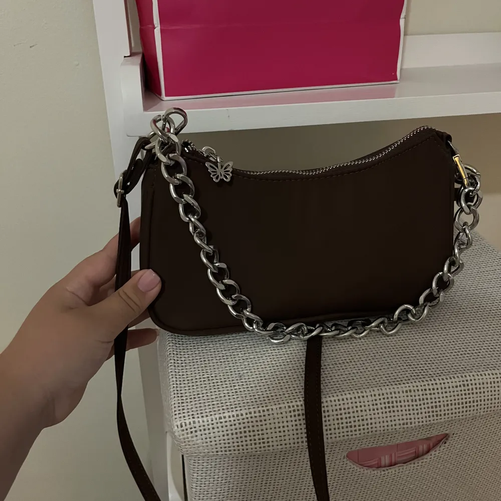 Jättefin väska från Bershka, aldrig kommit till användning❤️ den har en jättegullig fjäril på dragkedjan, det går att ta av den vanliga bandet och kedjan om man vill, man ser de på bild nummer 3❤️ den är brun men ser väldigt mörk ut på bilden. Laukut & Käsilaukut.