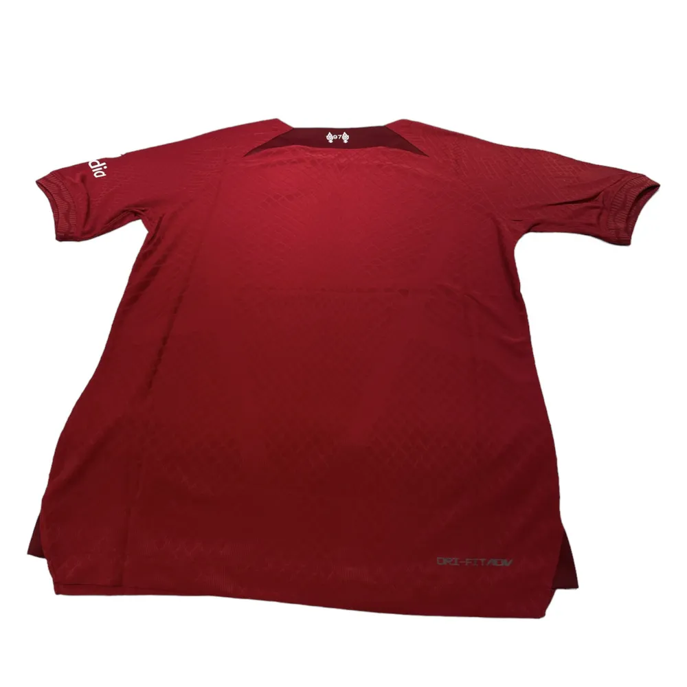 En Liverpool tröja i storlek s som är röd. Den är perfekt passande och av hög kvalitet. Dess andningsförmåga gör den idealisk för både matcher och träning.. T-shirts.