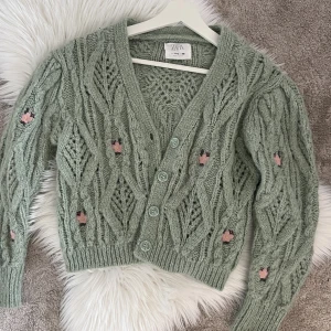 Grön stickad kofta - Grön stickad kofta med rosa broderade blommor på. Lite Matilda djerf feeling. Den är från Zaras barnavdelning men passar mig som vanligt vis har storlek S. Perfekt sommar kofta att ha över sig. 