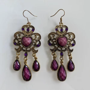 Örhängen med lila stenar💜 - Säljer dessa jättefina guldiga örhängen med lila stenar och en hjärtformad sten i mitten. Köpta utomlands, knappt använda💖