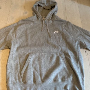 Nike luvtröja - Grå Nike hoodie. Köpt 2022 vinter. Skönt material inuti som är ull liknande. Annars som nyskick och använd få gånger, 9/10 skick. Nypris 600kr från stadium.