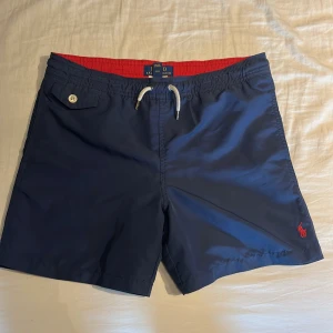 Mörkblåa polo Ralph Lauren badbyxor - Mörkblåa Polo Ralph Lauren badbyxor med röd detalj inuti vid midjan Skick: 9,5/10