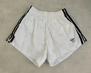 Vintage vita Adidas shorts - Old school Adidas shorts stl D7, uppskattar till ca stl M. I bra skick, enstaka fläckar förekommer men inget som syns direkt - se bilder. Material: bomull 