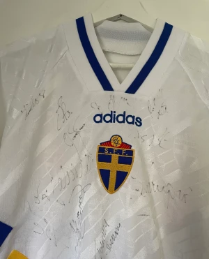 Sverige VM 1994 signerad fotbollströja  - En riktigt cool tröja som är omöjligt att få ta på idag, bortatröja från 94 som dessutom är signerad.