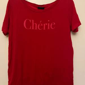 En röd T-shirt dom knappt är använd.  Med tryck på bröstet. ”Cherie” 
