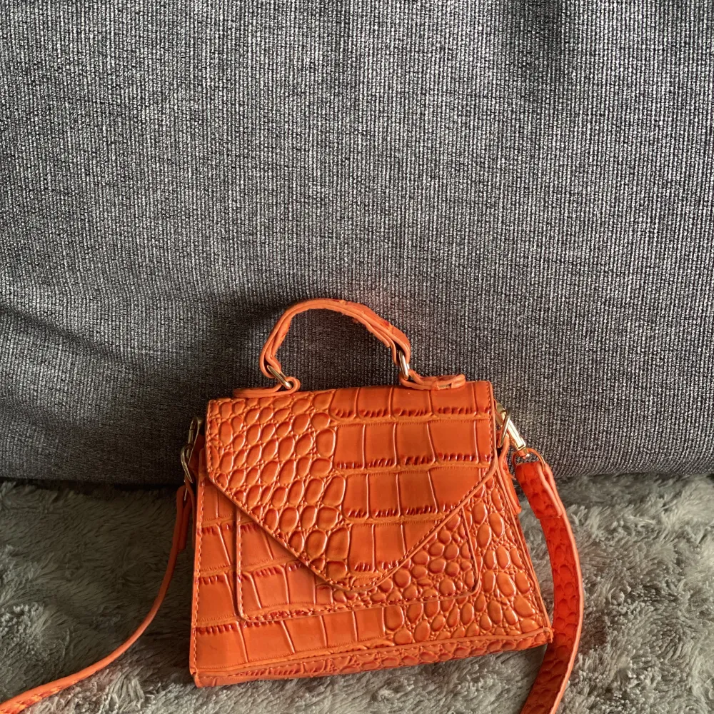 Jätte fin liten orangeväska, den har ett långt band som man kan justera. Väskor.