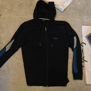 (M) BOSS Hoodie ”SAGGY” - Säljer BOSS Hoodie ”SAGGY”. Nyskick, säljer då jag har tröttnat på den. Nypris: 1600kr