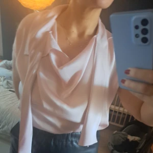 By Marlene Birger  - Ljusrosa silkig knytblus med halsprapering. Snygg öppen som knuten. Mycket gott skick Stl 38