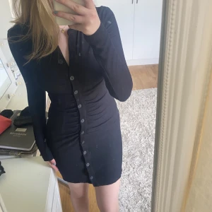 Helt oanvänd svart långklänning med knappar! - Helt oanvänd ribbad svart klänning med knappar i storlek M. 